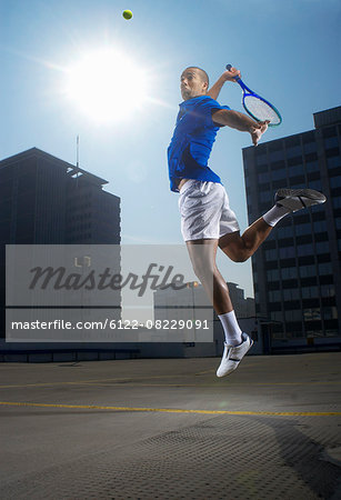 Tennis player jumping on rooftop court