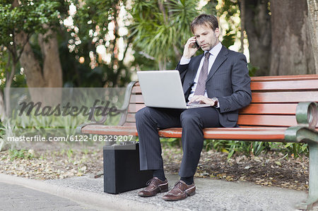 Businessman working on laptop in park