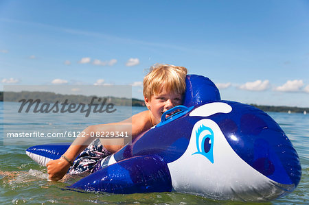 Boy floating in lake with toy whale