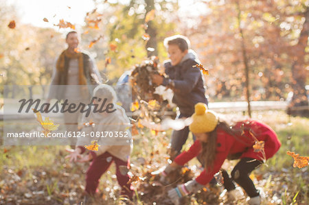 Family playing in autumn leaves at park