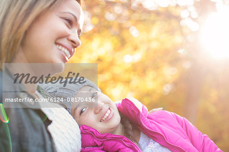 Portrait affectionate mother and daughter below autumn leaves