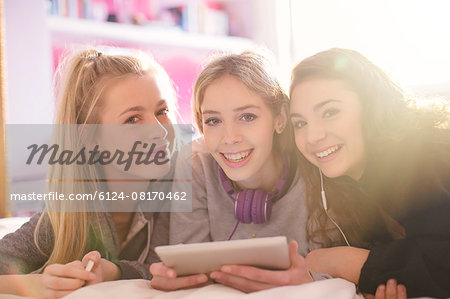 Portrait of smiling teenage girls using digital tablet