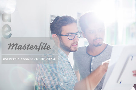 Creative businessmen reviewing paperwork in sunny office