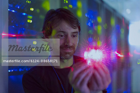 Server room technician holding illuminated computer chip Server room technician holding illuminated computer chip