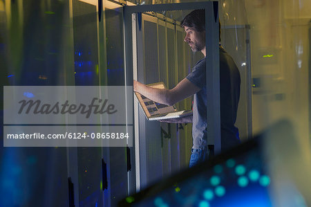 Server room technician with laptop at panel