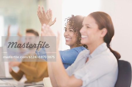 Businesswomen smiling and clapping in meeting
