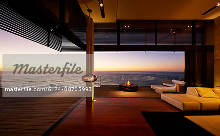 Fire pit and hanging fireplace on modern luxury patio with sunset ocean view
