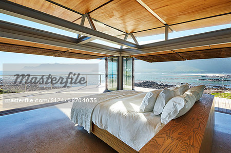 Modern luxury bed open to patio with sunny ocean view