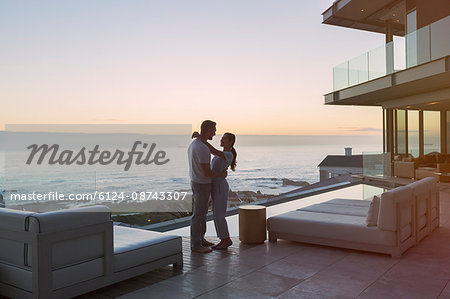 Affectionate couple hugging on luxury patio with ocean view Affectionate couple hugging on luxury patio with ocean view