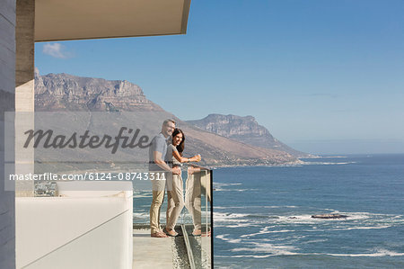 Couple looking at sunny ocean view from luxury balcony