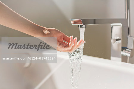 Woman touching water from modern bathtub faucet