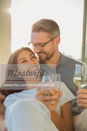 Affectionate couple smiling and drinking white wine