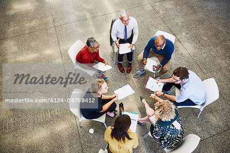Business people discussing paperwork in meeting circle