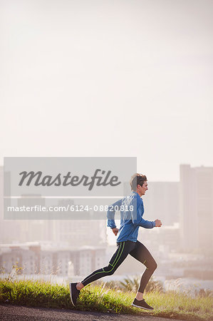 Male runner running on sunny urban city street