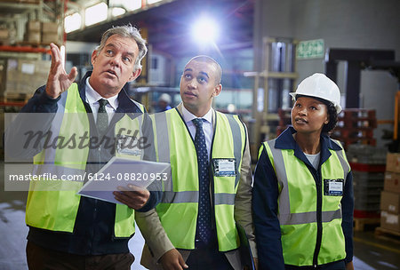 Managers and worker talking looking up in distribution warehouse Managers and worker talking looking up in distribution warehouse