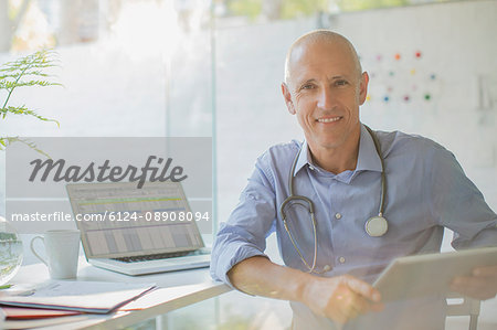 Portrait smiling male doctor with digital tablet in doctor’s office