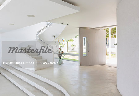 White foyer and spiral staircase in modern luxury home showcase interior