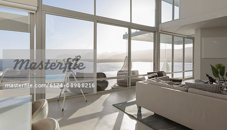 Sunny, tranquil modern luxury home showcase interior living room with telescope and ocean view