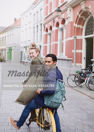 Portrait smiling young man and woman riding bicycle on city street