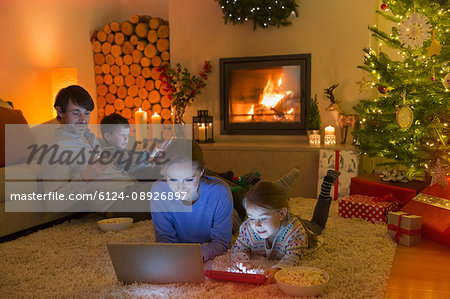 Family relaxing, using laptop, digital tablet and cell phone in ambient Christmas living room