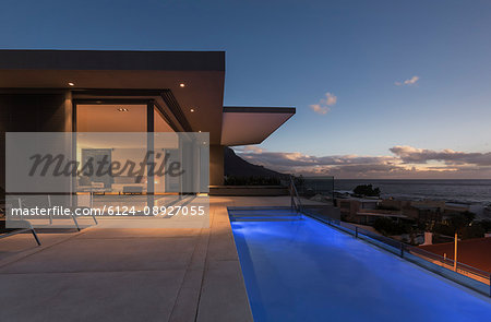 Tranquil blue lap swimming pool outside modern luxury home showcase exterior at dusk