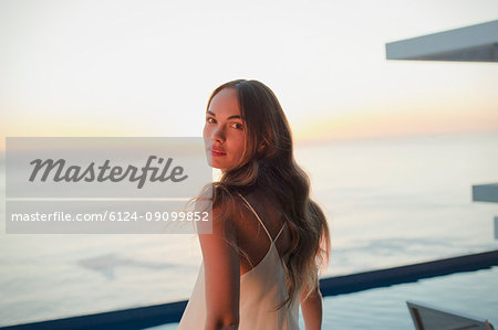 Portrait serious, beautiful woman on luxury patio with sunset ocean view