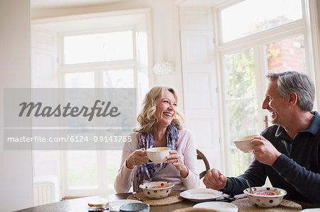 Smiling, happy mature couple eating breakfast, drinking coffee