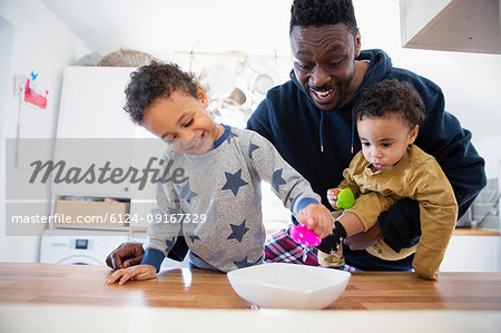 Father and sons playing with toys in kitchen
