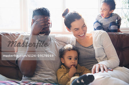 Laughing, happy multi-ethnic family on living room sofa Laughing, happy multi-ethnic family on living room sofa