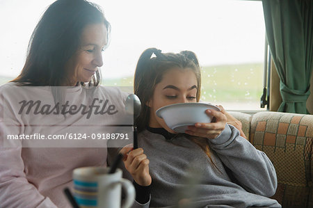 Mother watching daughter finishing cereal in motor home