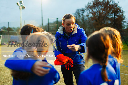 Girls soccer team listening to coach on field at night