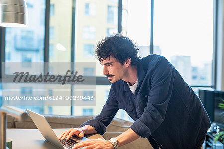 Focused man using laptop in urban apartment kitchen