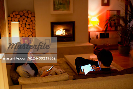 Couple using digital tablet and smart phone in living room