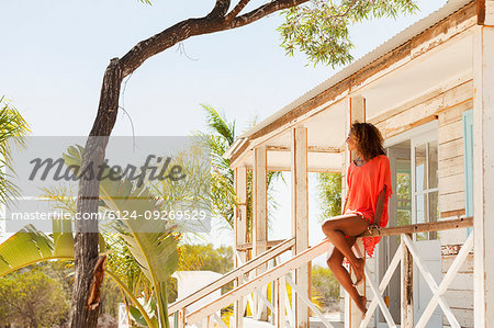 Young, serene woman relaxing on sunny beach hut patio