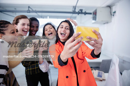 Happy businesswomen celebrating, taking selfie in office