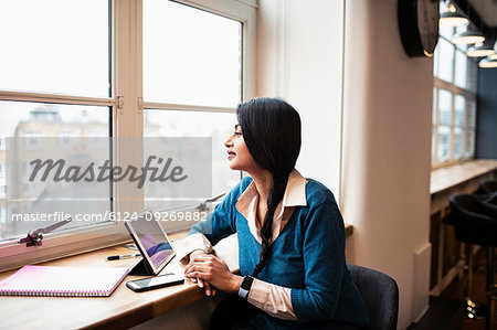 Thoughtful businesswoman working at digital tablet in office window