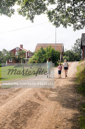 Sweden, Smaland, Vastervik, Hummelstad, Rear view of children (6-7, 10-11, 12-13) walking along village road