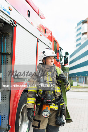 Sweden, Female firefighter with equipment standing next to fire truck