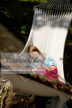 Sweden, Dalarna, Falun, Young woman lying on hammock in forest