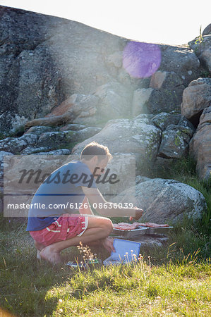 Sweden, Swedish West Coast, Halland, Kungsbackafjorden, Man cooking food on barbecue grill