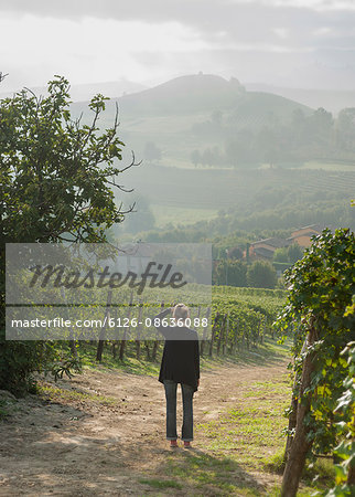 Italy, Piedmont, Woman looking at view on road along vineyard