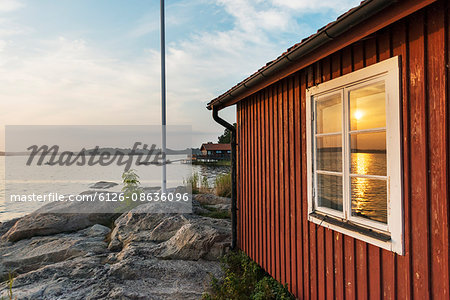 Sweden, Uppland, Stockholm archipelago, Nasslingen, Reflection of sun in window at sunset