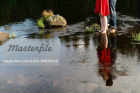 Sweden, Vastmanland, Bergslagen, Svartalven, Low section of mid adult couple standing in river