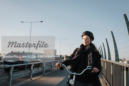 Sweden, Sodermanland, Stockholm, Vasterbron, Young woman walking with bike