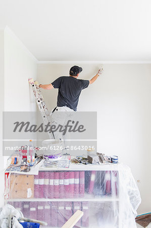 Sweden, Mature man painting wall