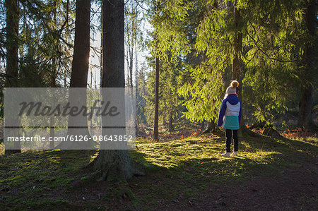 Sweden, Smaland, Anderstorp, Girl (10-11) standing in forest, rear view