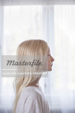 Sweden, Side view of blonde girl (10-11) in front of white curtains