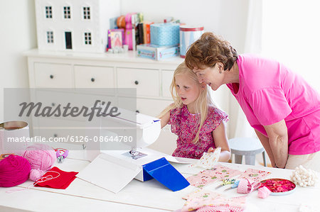 Finland, Grandmother with granddaughter (8-9) playing with sewing machine