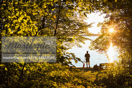 Sweden, Skane, Immeln, Silhouette of man standing with oar at sunset