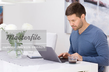 Sweden, Mid adult man using laptop